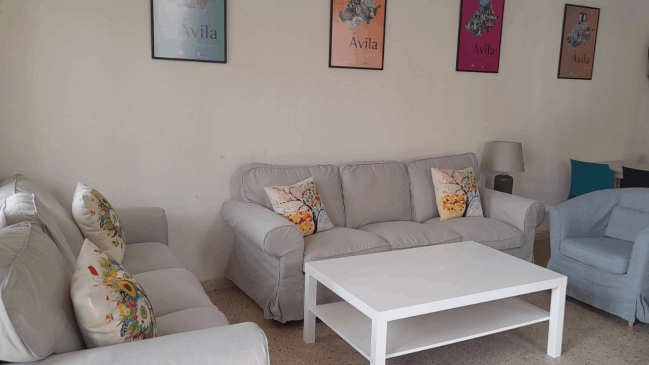 Un salón con tres sillones y una mesa blanca en medio