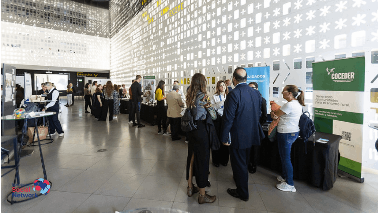 Un grupo de personas hablando en una sala con unos photocall de COCEDER y de otras entidades