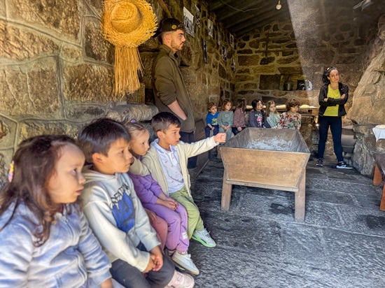 unos niños sentados escuchando en un obrador de pan