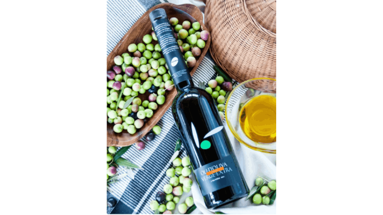 Imagen de una botella negra de aceite sobre unas aceitunas