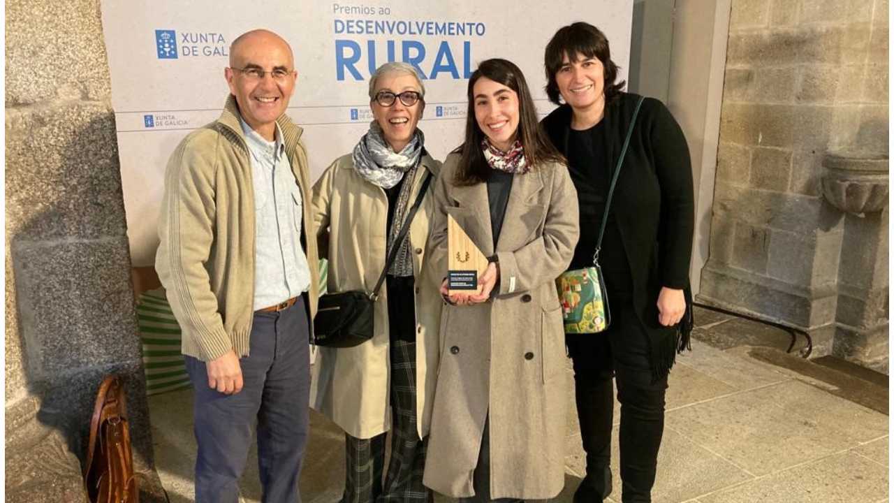 cuatro personas con un premio de la mano detrás de un cartel de la Xunta de Galicia