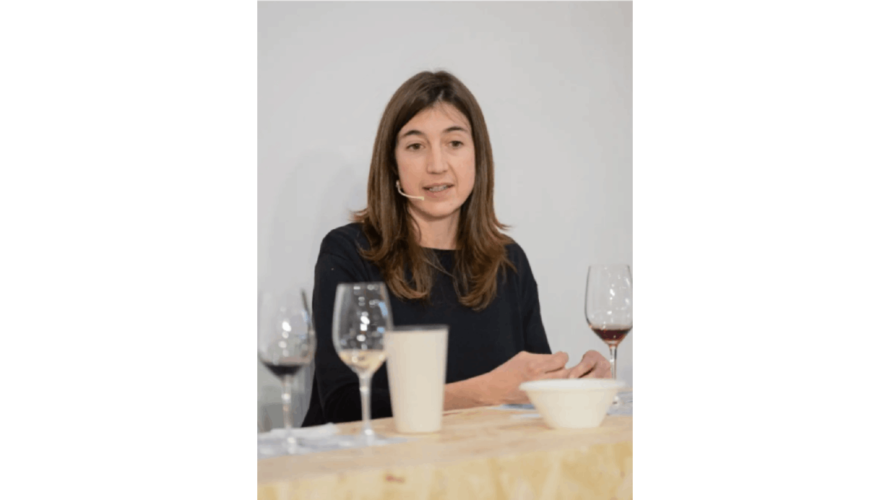 Una mujer delante de una mes con copas de vino