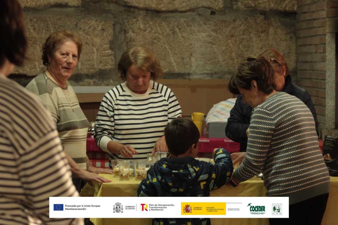 Grupo de mujeres y un niño alrededor de una mesa de cocina preparando recetas