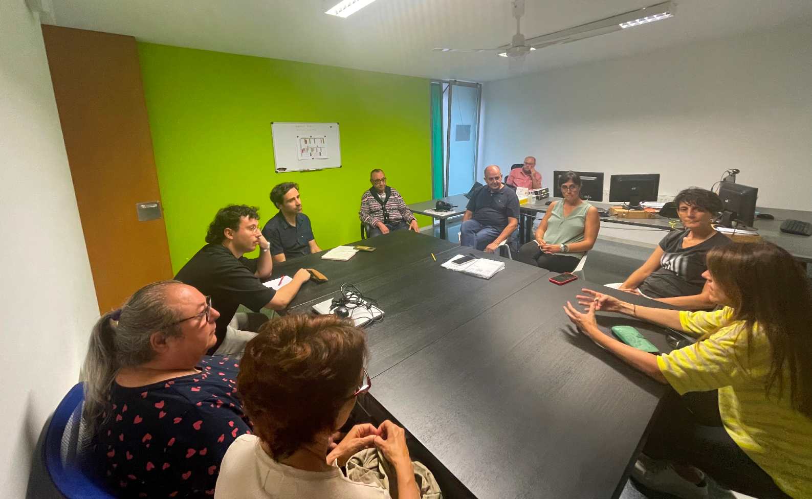 grupo de personas sentadas en reunión alrededor de una mesa 