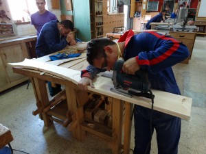 Grupo de personas en un taller de madera realizando actividades observados por un monitor