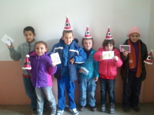 Grupo de niños con gorros de fiesta y mostrando una tarjeta