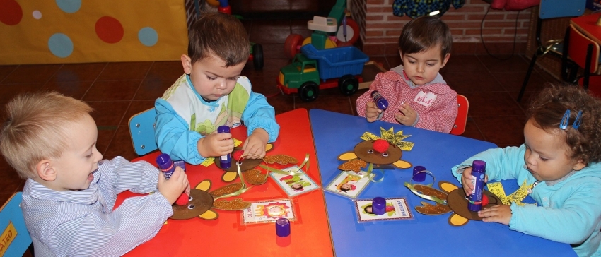 Grupo de niños pequeños alrededor de una mesa realizando actividades