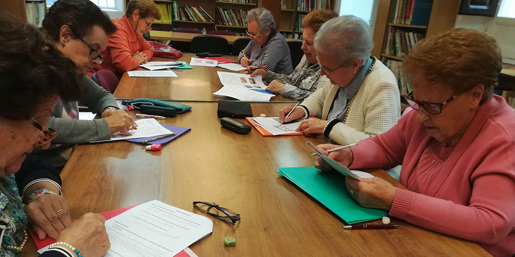 Personas mayores reunidas en una biblioteca realizando una actividad