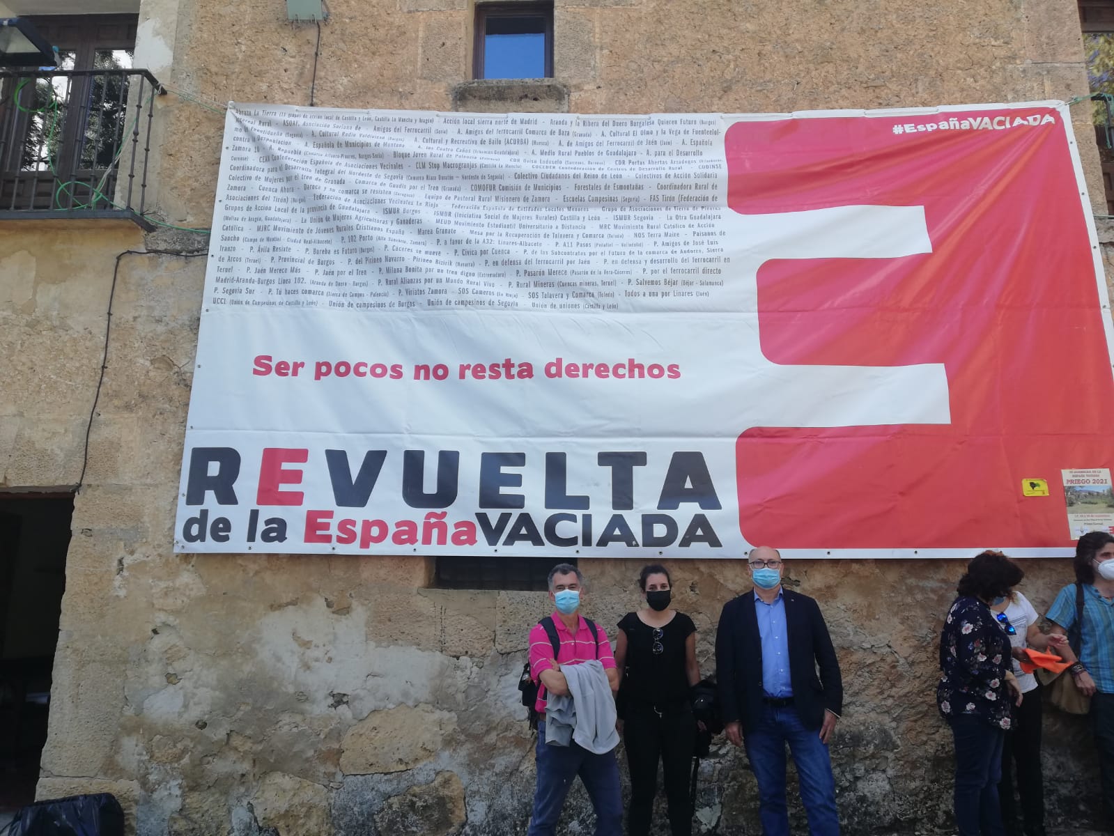Casa rural con una bandera de la revuelta de la España vaciada y unas personas posando delante de la misma 
