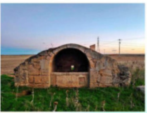 Fuente entre campo verde y árido