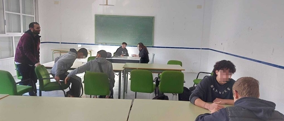 Aula con personas jóvenes sentada en parejas y un profesor mirándoles