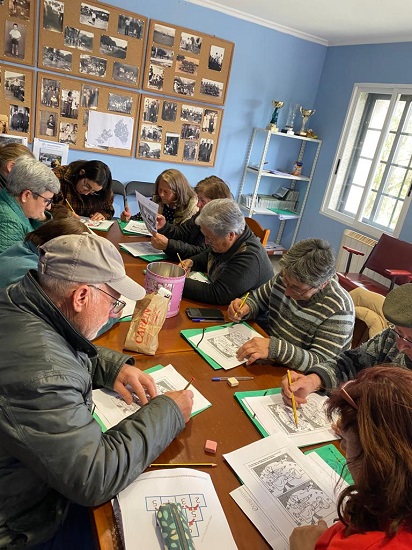 Grupo de personas mayores realizando una actividad sentados alrededor de una mesa