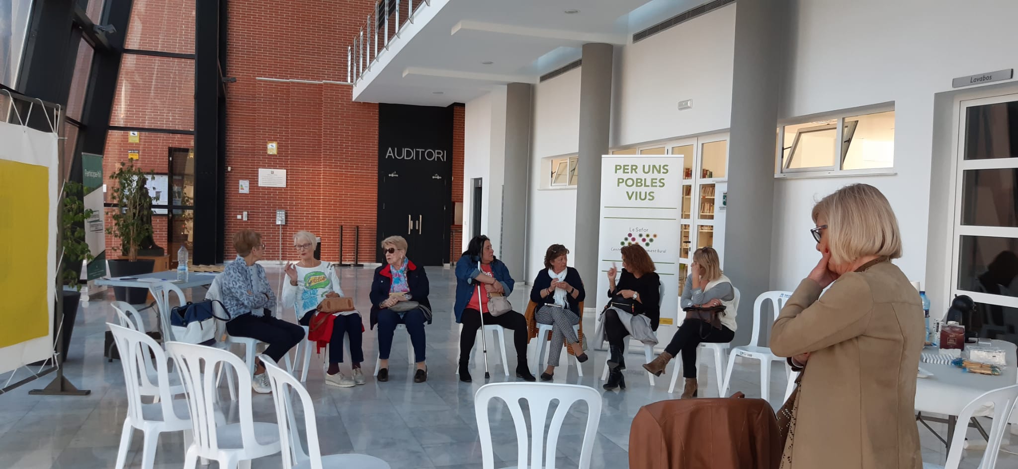 Grupo de personas sentadas en círculo en la sala de un auditorio asistiendo al diálogo sobre la vivienda