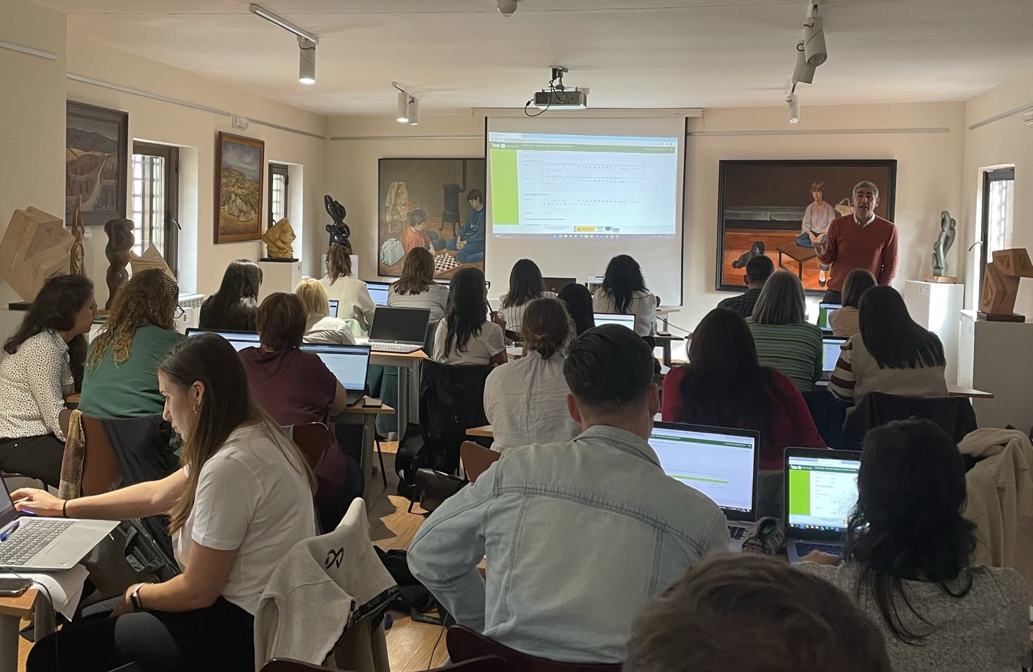 Grupo elevado de personas en un aula con portátiles asistiendo a la formación 