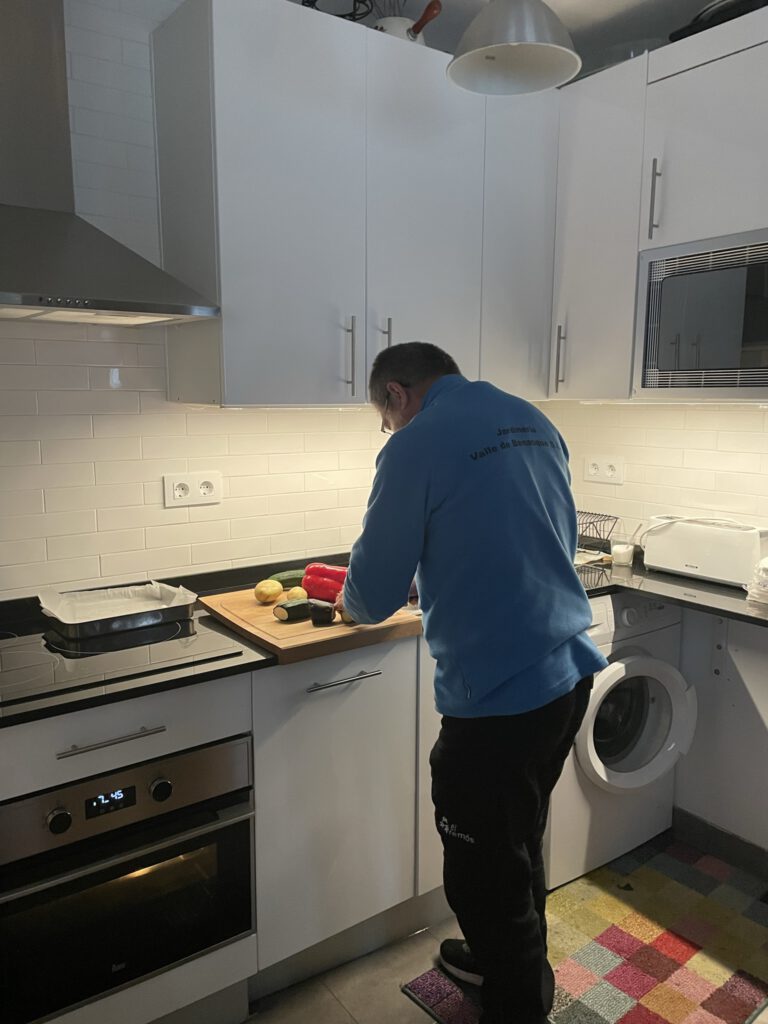 Un señor cortando verdura en una cocina