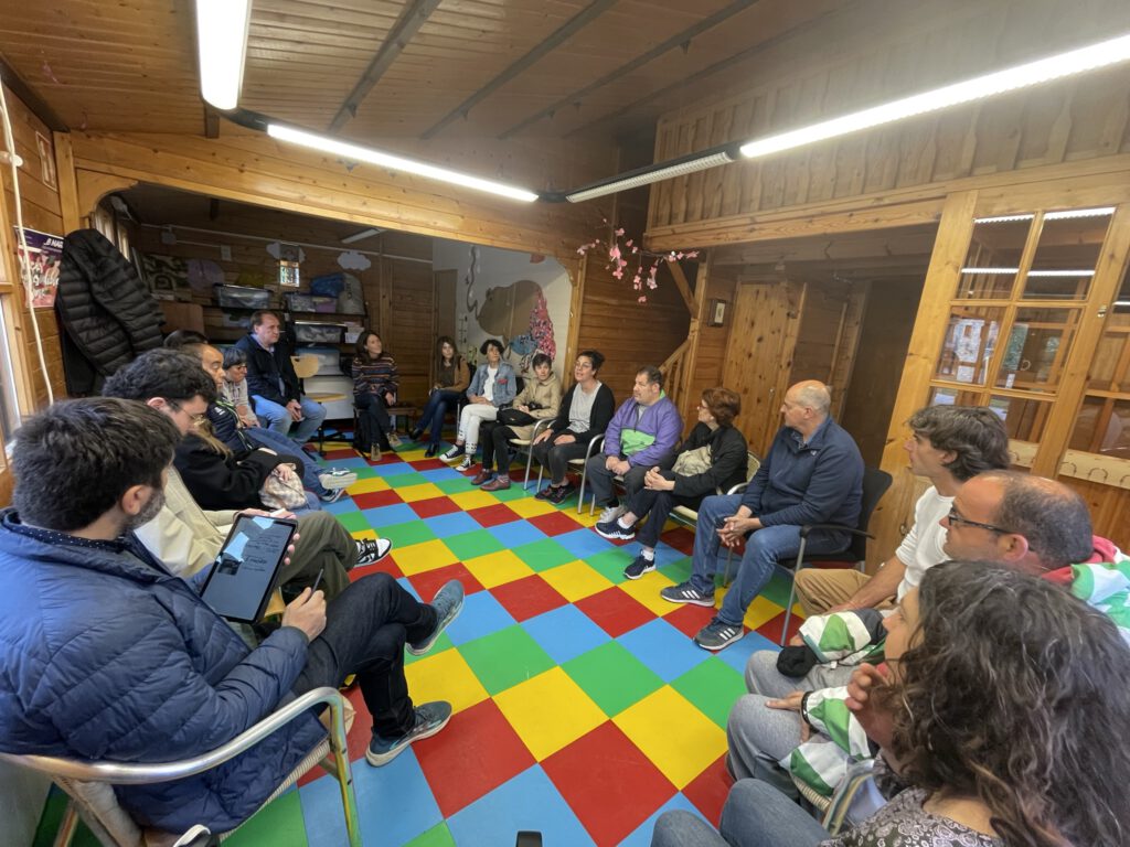 Grupo de personas sentadas en circulo en una sala de madera